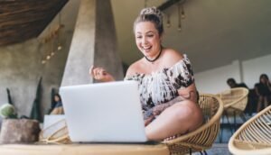 Smiling tattooed female digital nomad work on netbook