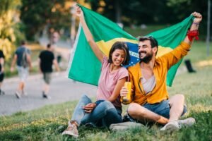 Young couple dancing at a festival in the park with a Brazil flag
