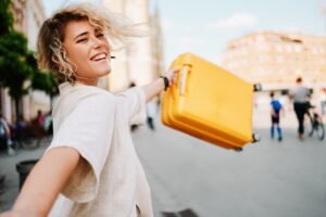 Young happy woman holds a traveling bag while exploring the city