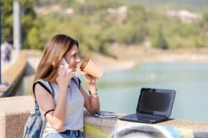 Digital nomad. Girl drinking coffee while working on the laptop.