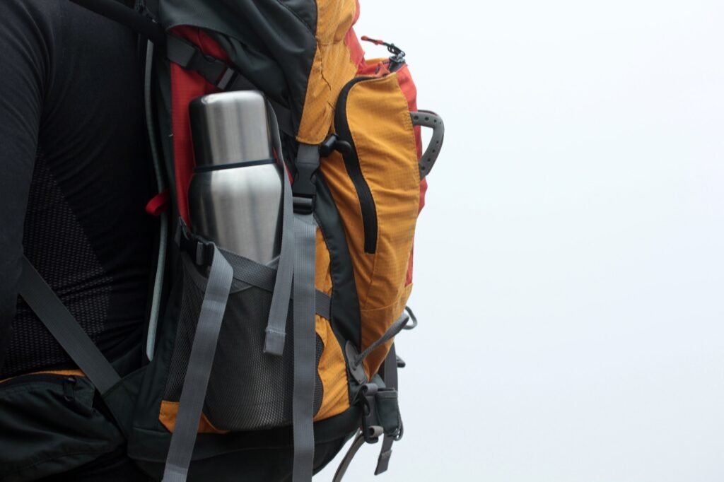 Steel thermos in the pocket of the backpack. Tourist Traveler bag. Adventure Walk.