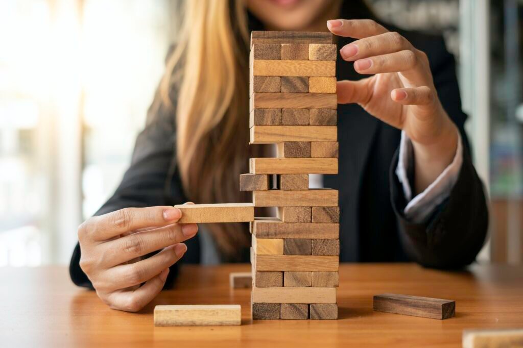 A businesswoman pulls a wooden block in the middle of the floor. It is like managing business risks