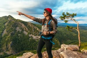 A young tourist pointing her finger at the mountains. Travel and hiking