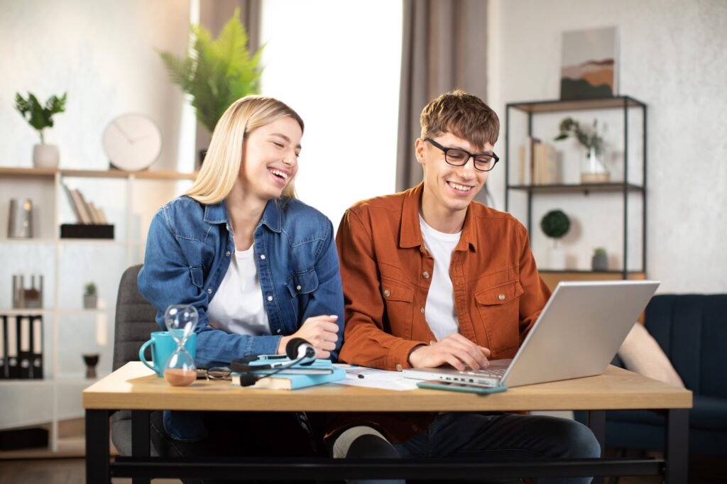 Young man and woman using laptop sitting at the table and studying together
