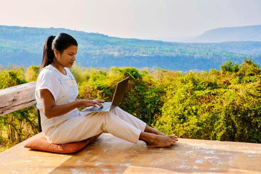 Young woman digital nomad traveler working online on laptop in the mountains