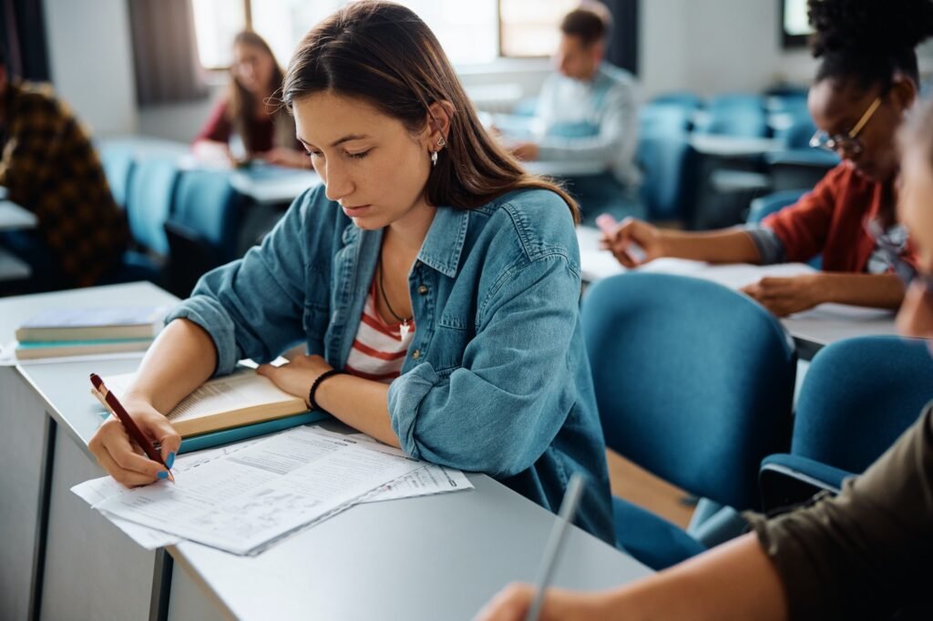 Young woman studying while attending a class in lecture hall.