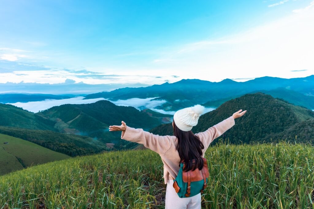 Young woman travelers looking at the sunrise and the sea of mist on the mountain in the morning