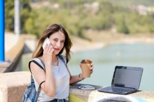 Digital nomad. Girl drinking coffee while working on the laptop.