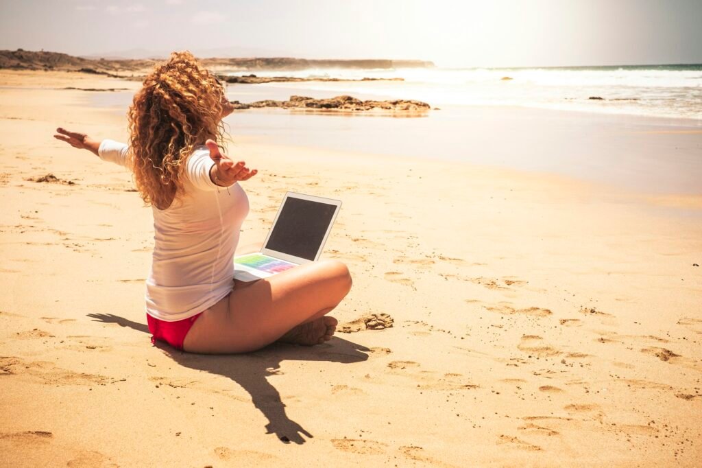 Freedom for smart working and digital nomad people lifestyle - happy free woman sitting on beach