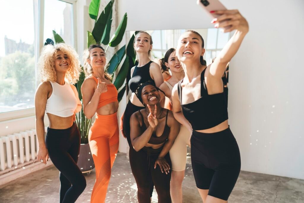 Group of positive sportswomen taking selfie in gym