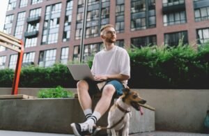 Serious young digital nomad browsing laptop in city street