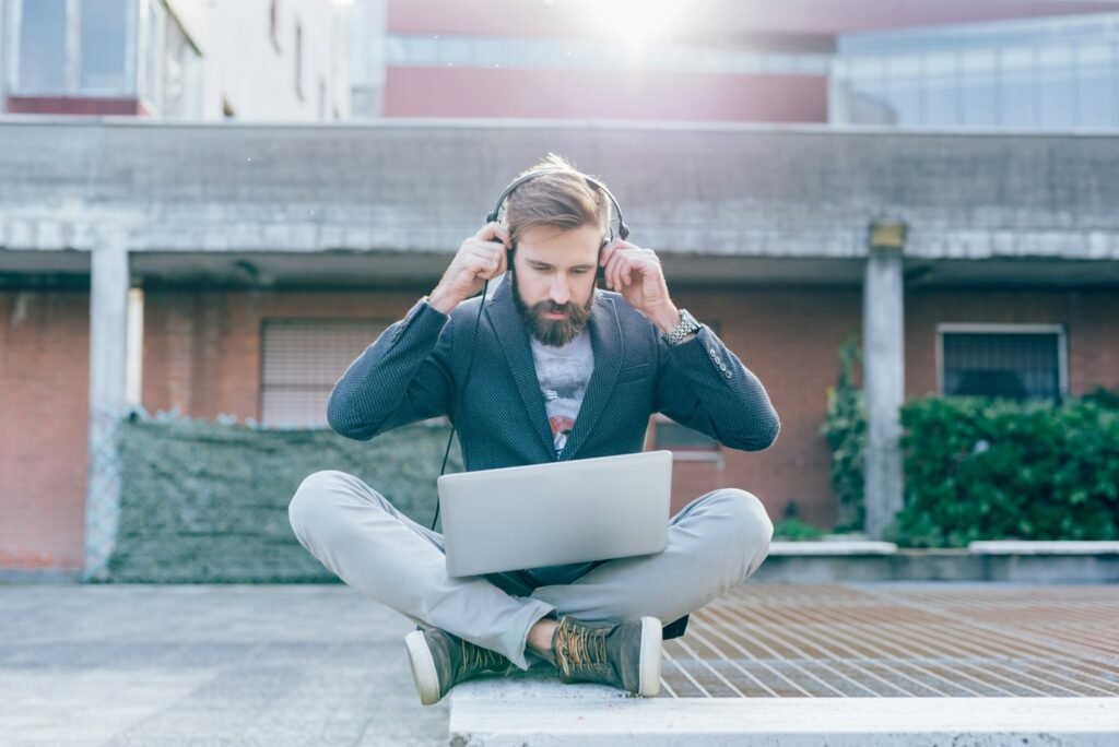 Young bearded man using computer and headphones