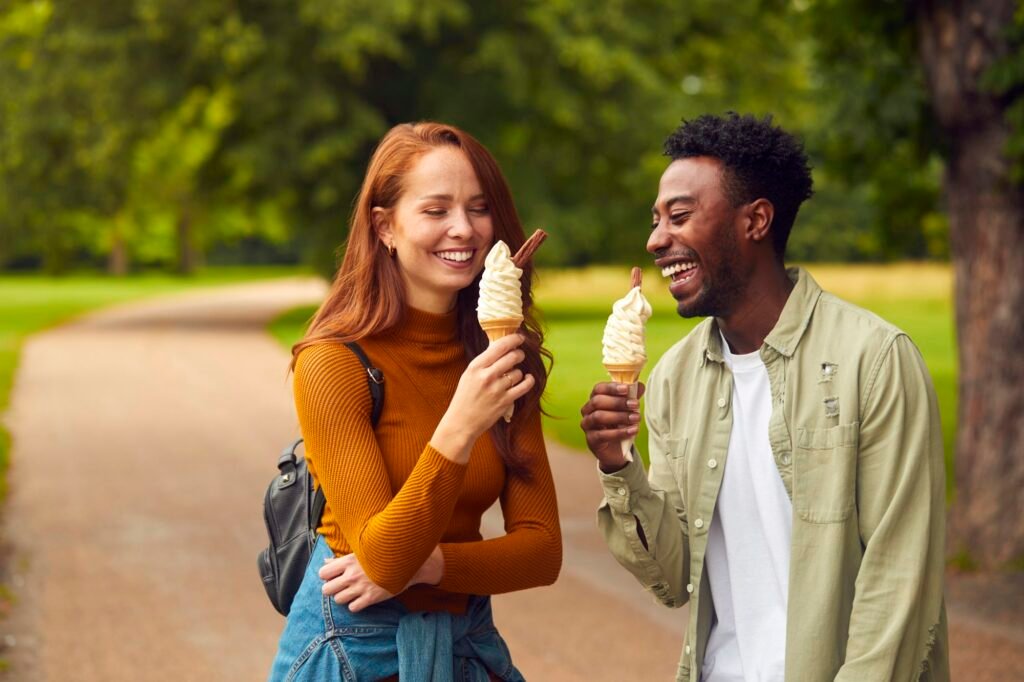 Young Couple Travelling Through City Together Eating Ice Creams In Park
