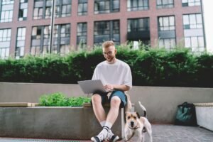 Young male digital nomad working on laptop remotely in city street