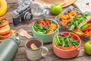 food travel lunch box with sandwich, vegetables, fruits and water, concept of vacation, tourism